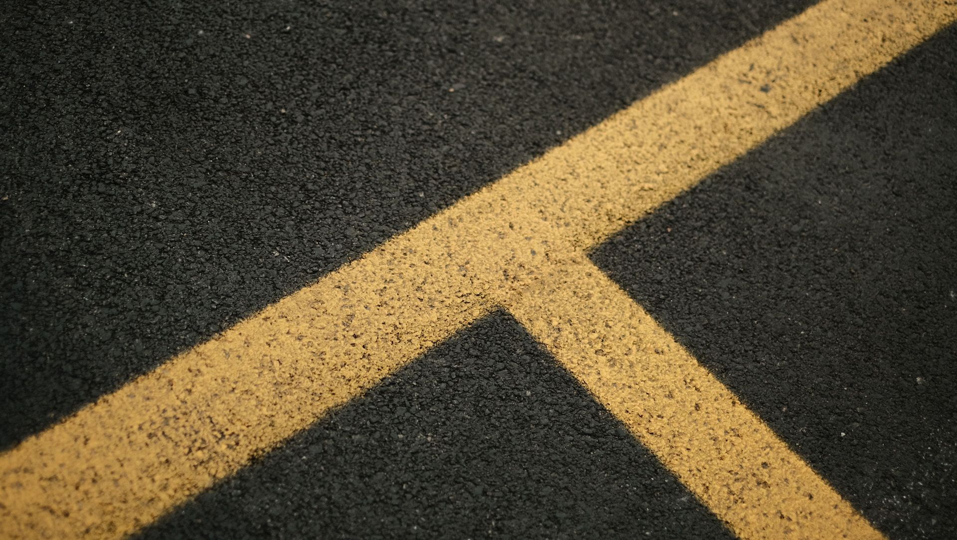 From above of asphalt road with bright yellow marking lines crossing between each other