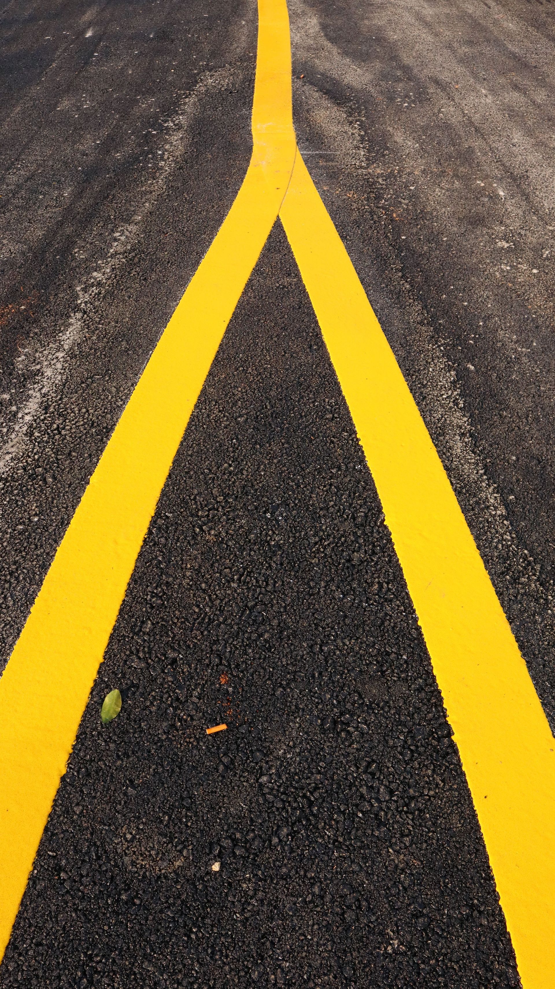 Close-up view of intersecting yellow road lines on fresh asphalt.